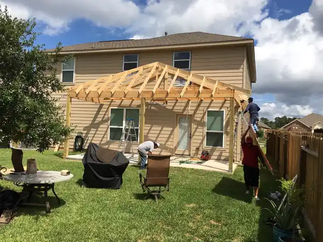 Crew framing a gabled patio cover on a two-storey home