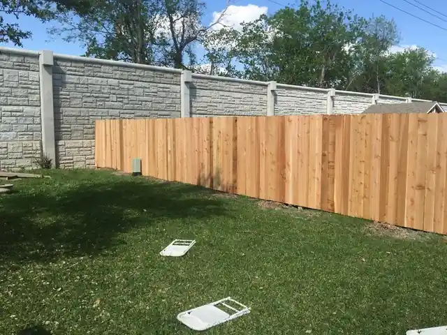Long run of new cedar fence against a stone wall