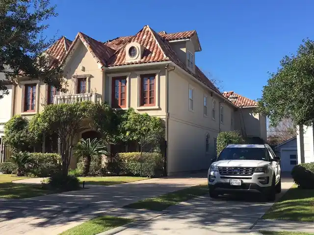 Stucco home with a red clay barrel tile roof, dormers and arched windows
