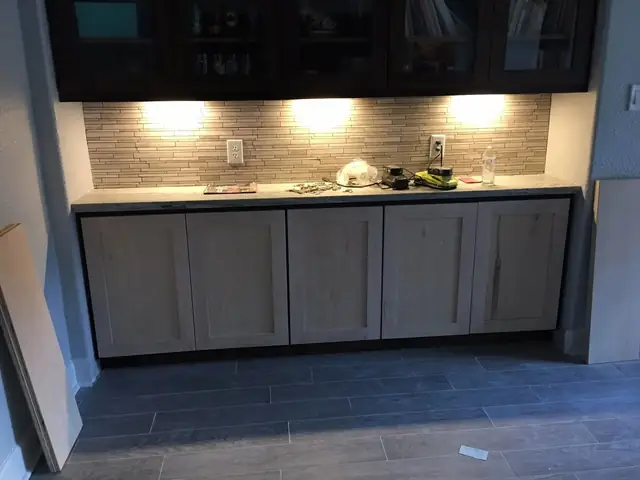 Built-in cabinets with a stone backsplash and under-cabinet lighting