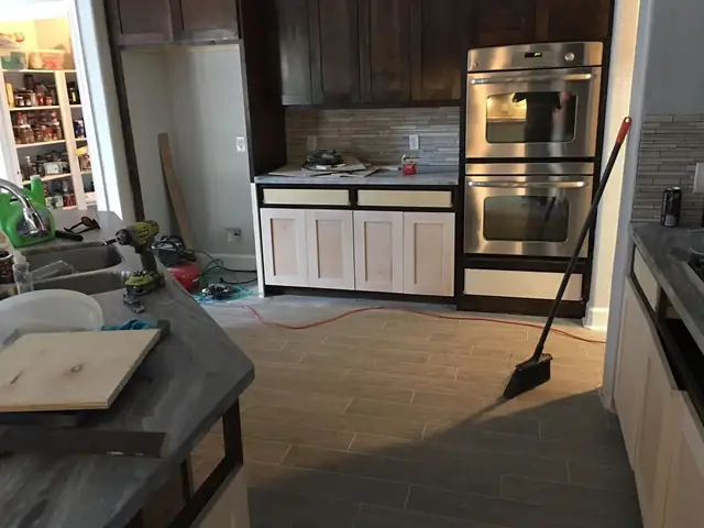Kitchen mid-rebuild after Hurricane Harvey with new cabinets, double wall ovens and plank tile floor