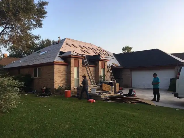 New roof sheathing on a brick ranch home with crew and ladders